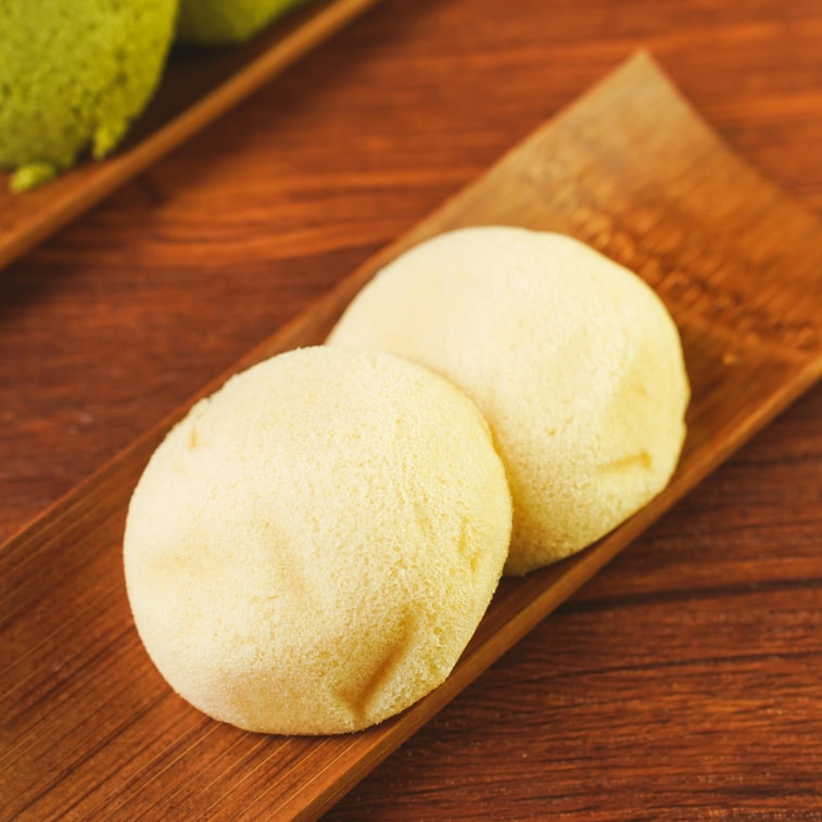 Image showing the Ichioka Seika Custard Cream Steamed Cake outside of its packaging, highlighting the soft steamed texture and custard-filled center.