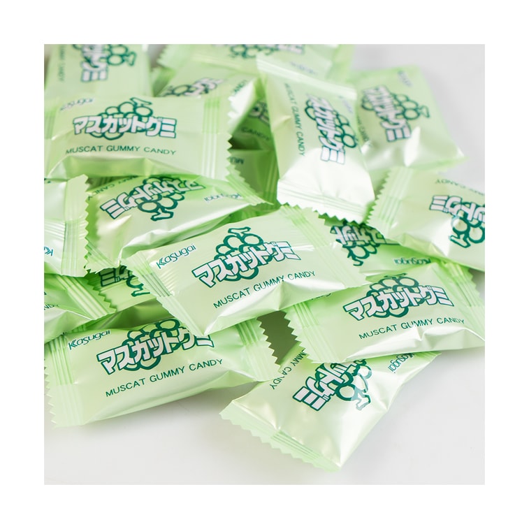 A portrait image displaying individually wrapped pieces of KASUGAI Frutia Muscat Gummy Candy placed outside the packaging on a white surface.