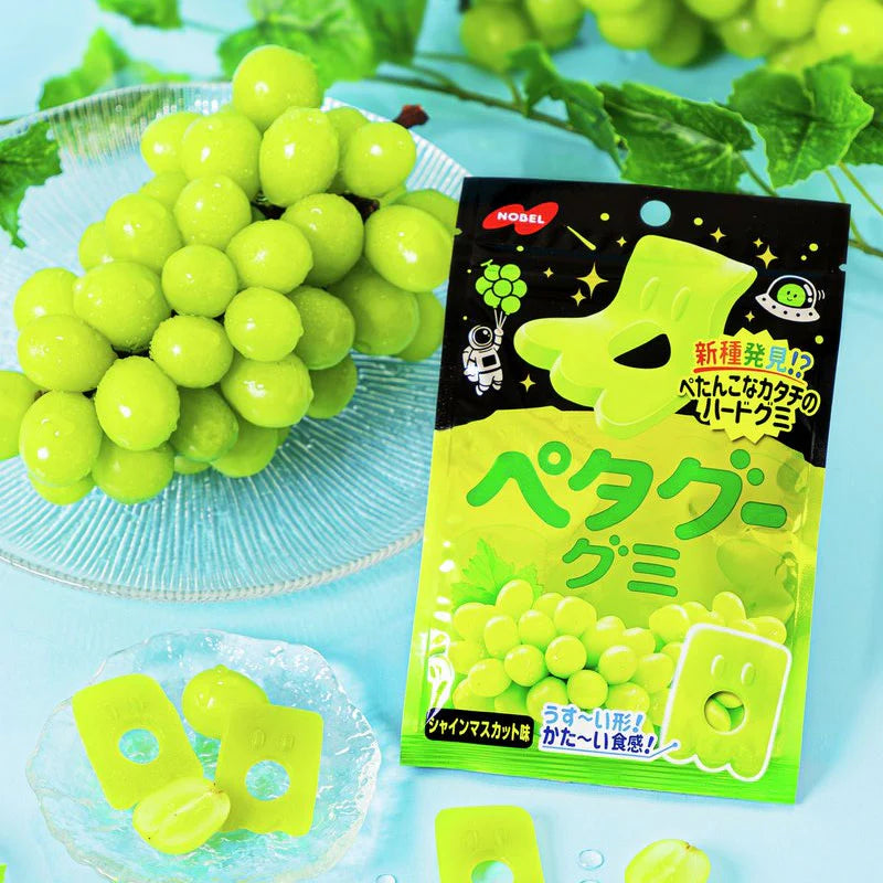 Front view of the NOBEL Petagu Shine Muscat gummy package with several gummies displayed outside the bag, showing their soft, chewy texture against a white backdrop.