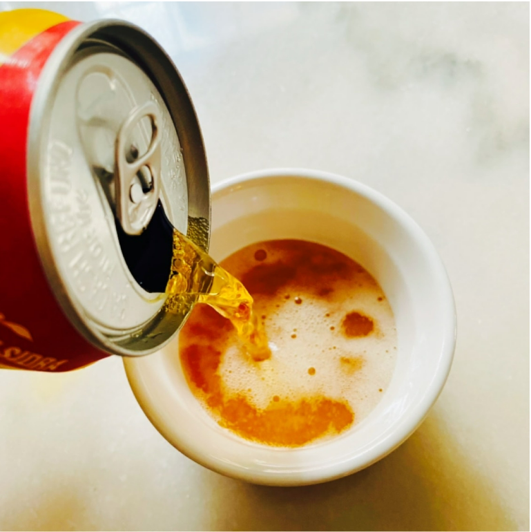 Image showing the Apple Sidra apple soda poured into a cup, highlighting its fizzy golden color and bubbly carbonation.