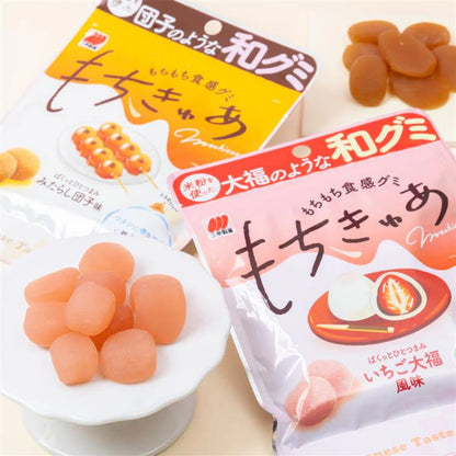 Portrait image of the opened SANKO Seika Mochicure Strawberry Daifuku gummies displayed beside the package, highlighting their soft, mochi-like texture and strawberry-inspired appearance.