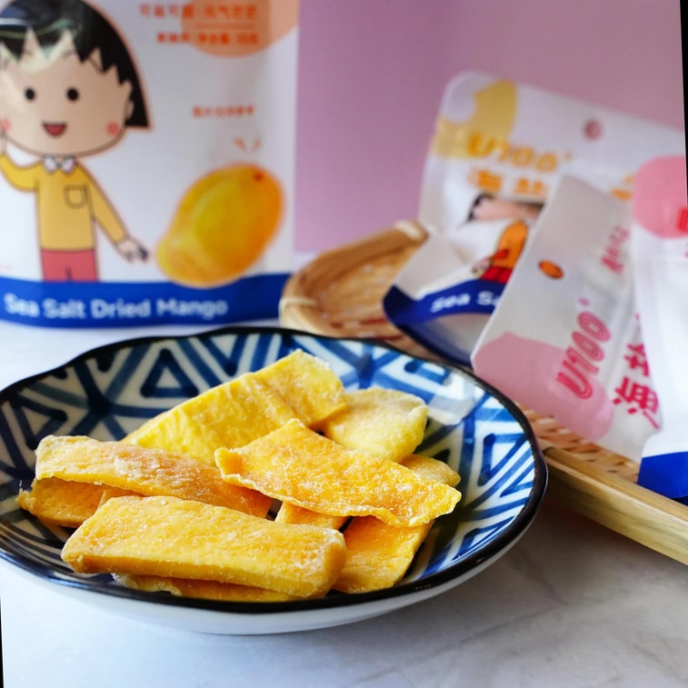 Image of the U100 Chibi Maruko-chan dried mango pieces displayed outside the bag on a white background, showing their chewy texture and lightly salted surface.